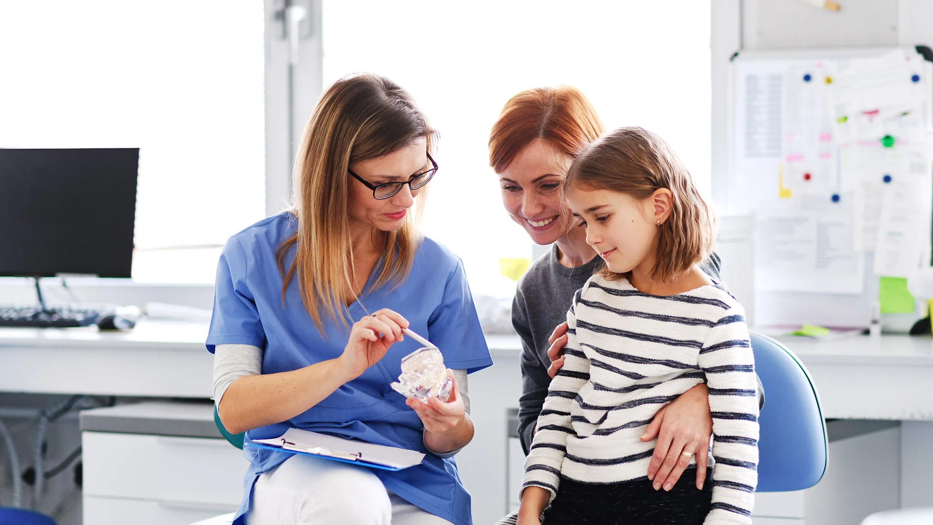 Young girl at the dentist with mother and dentist