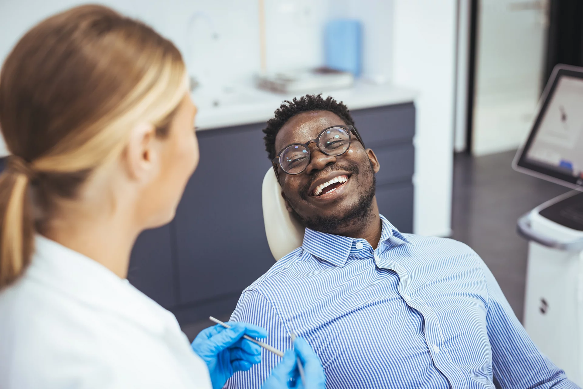 Smiling guy in dentist chair looking with trust at his doctor, close up.