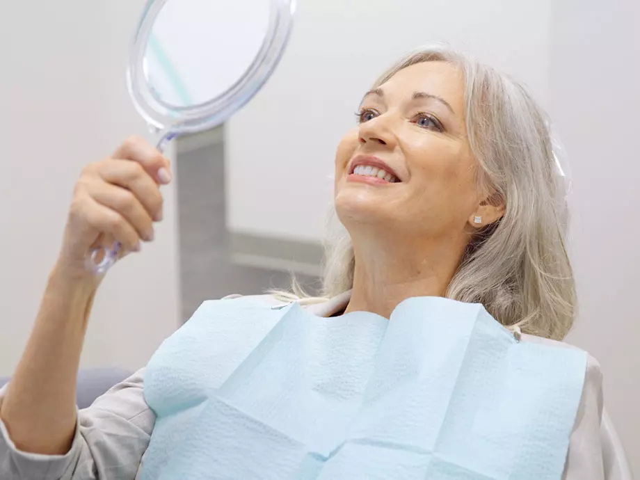 Female patient looking in a hand-held mirror