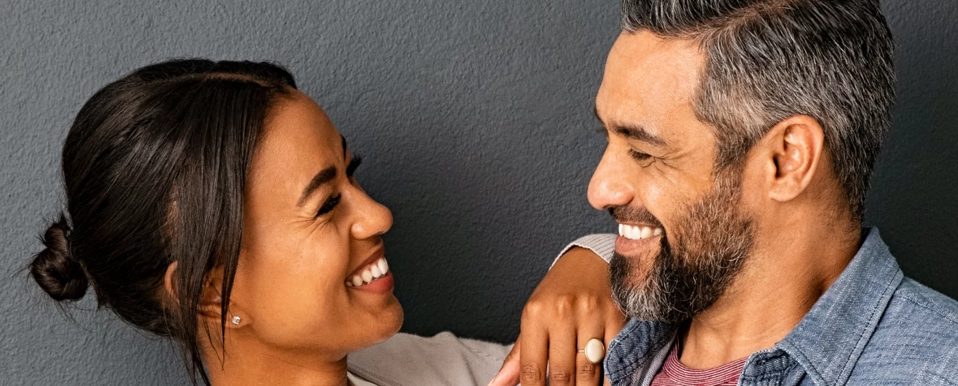Man and woman smiling at each other with gray background