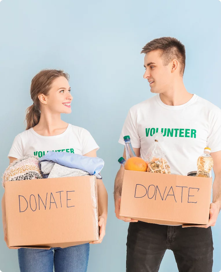 Two volunteers holding donate boxes filled with donations