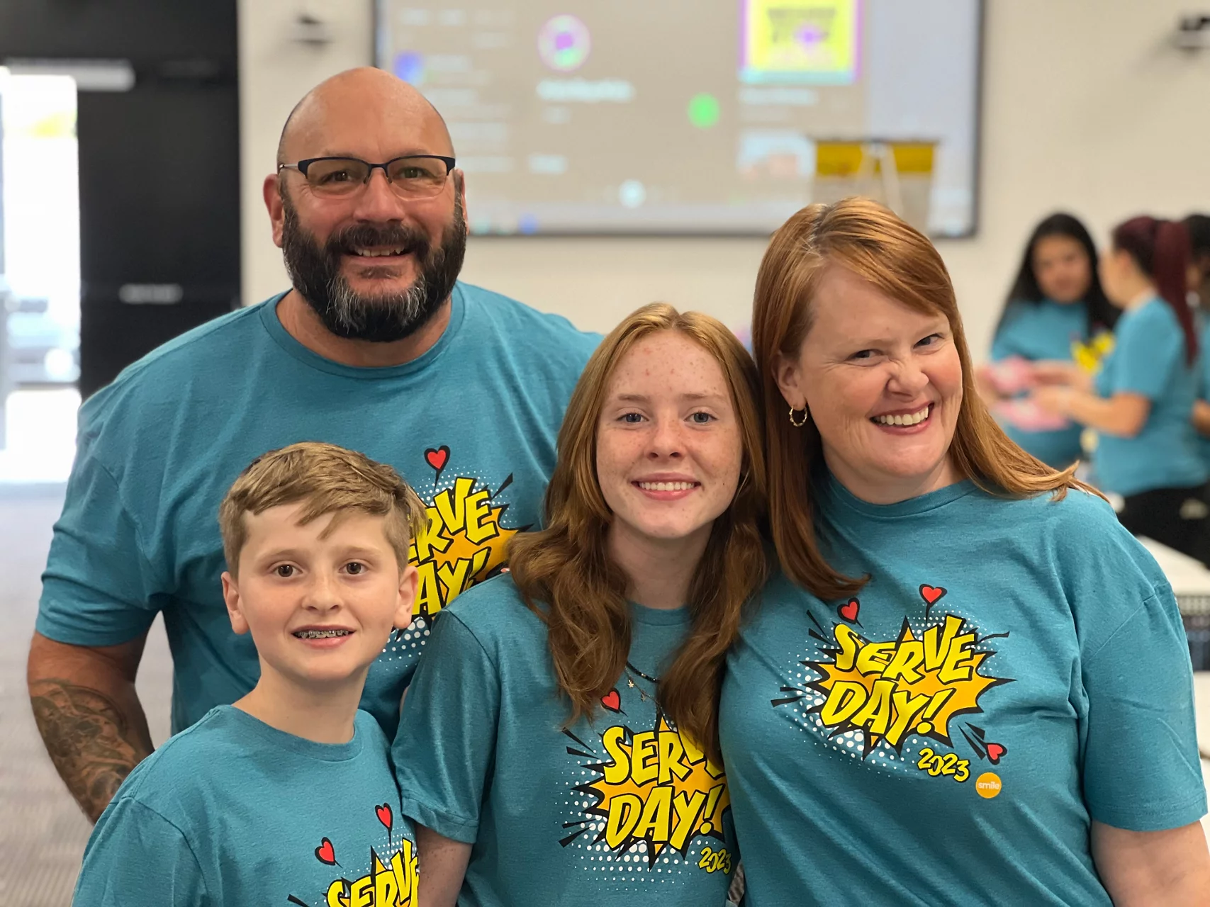A family smiling at the camera for an event, Serve Day 2023