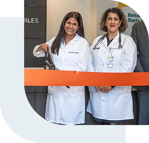 Two female dentists cutting a ribbon at an opening ceremony