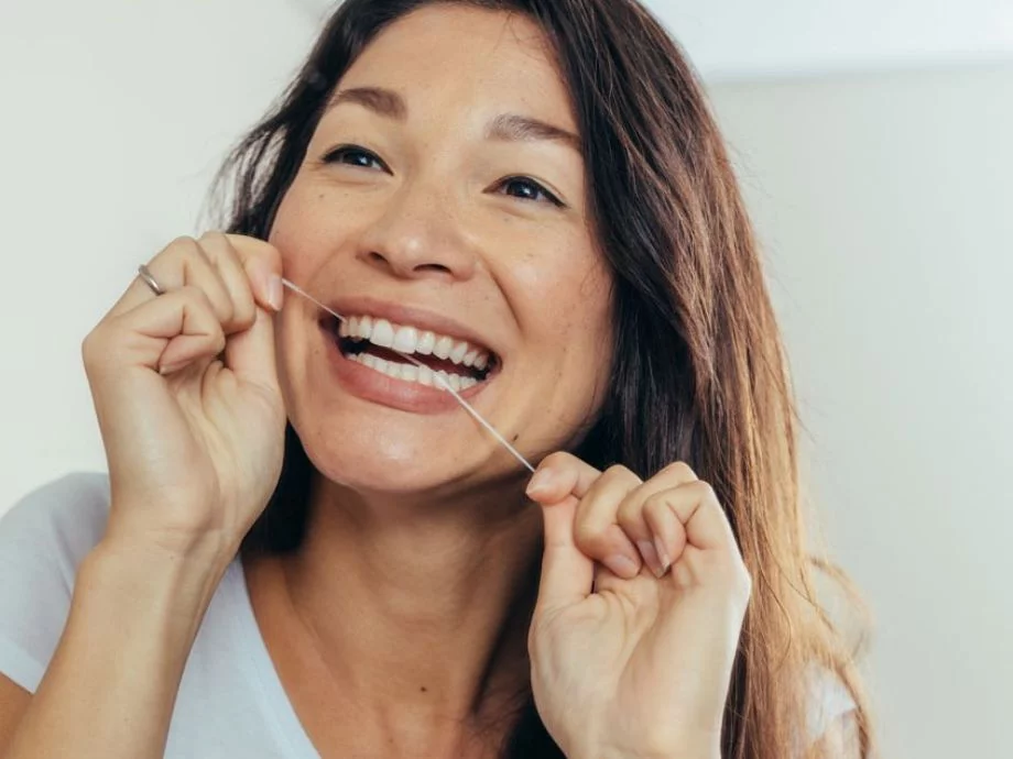 women flossing her teeth in front of mirror