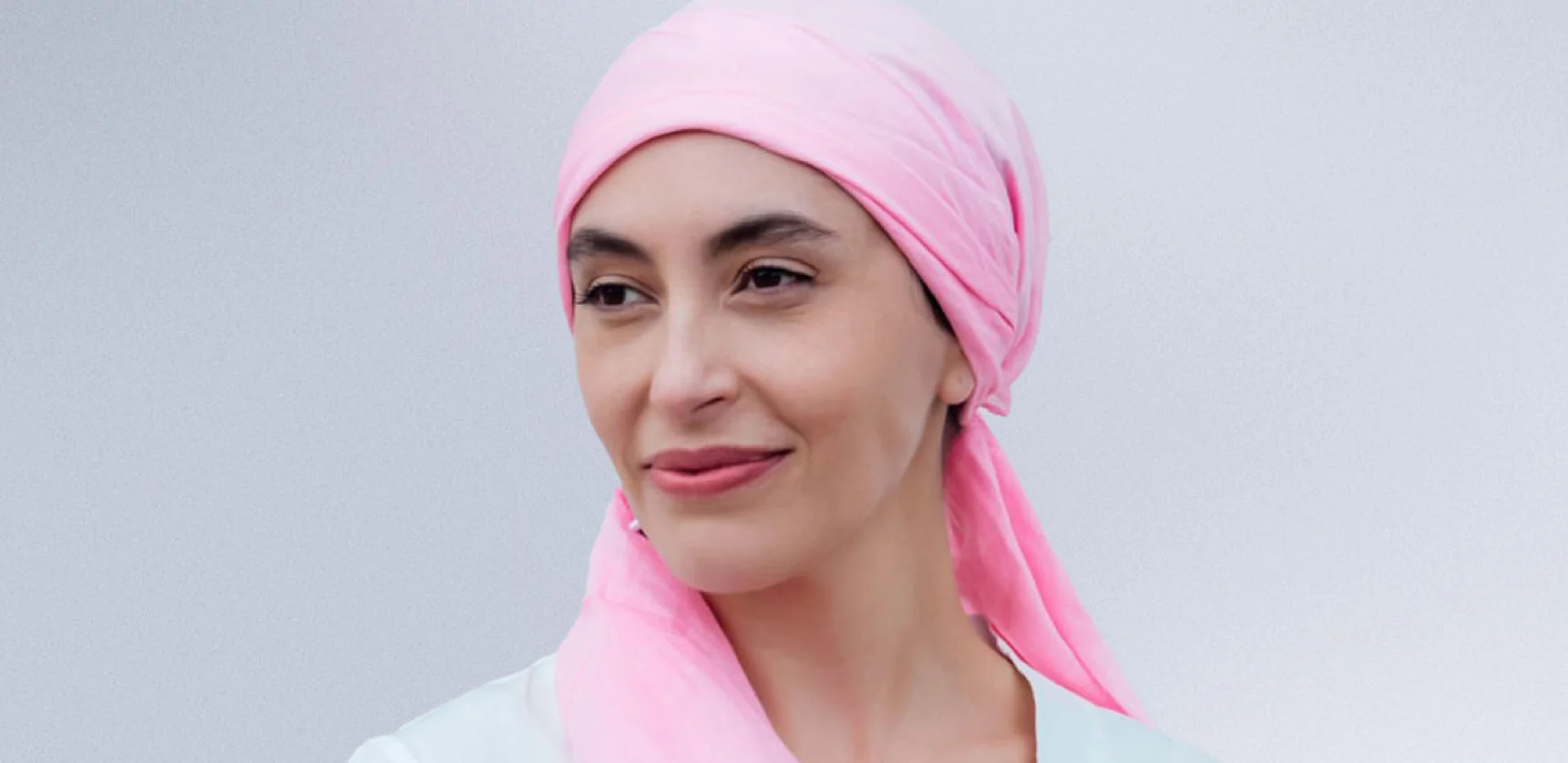 Woman wearing a pink head scarf looking away from the camera