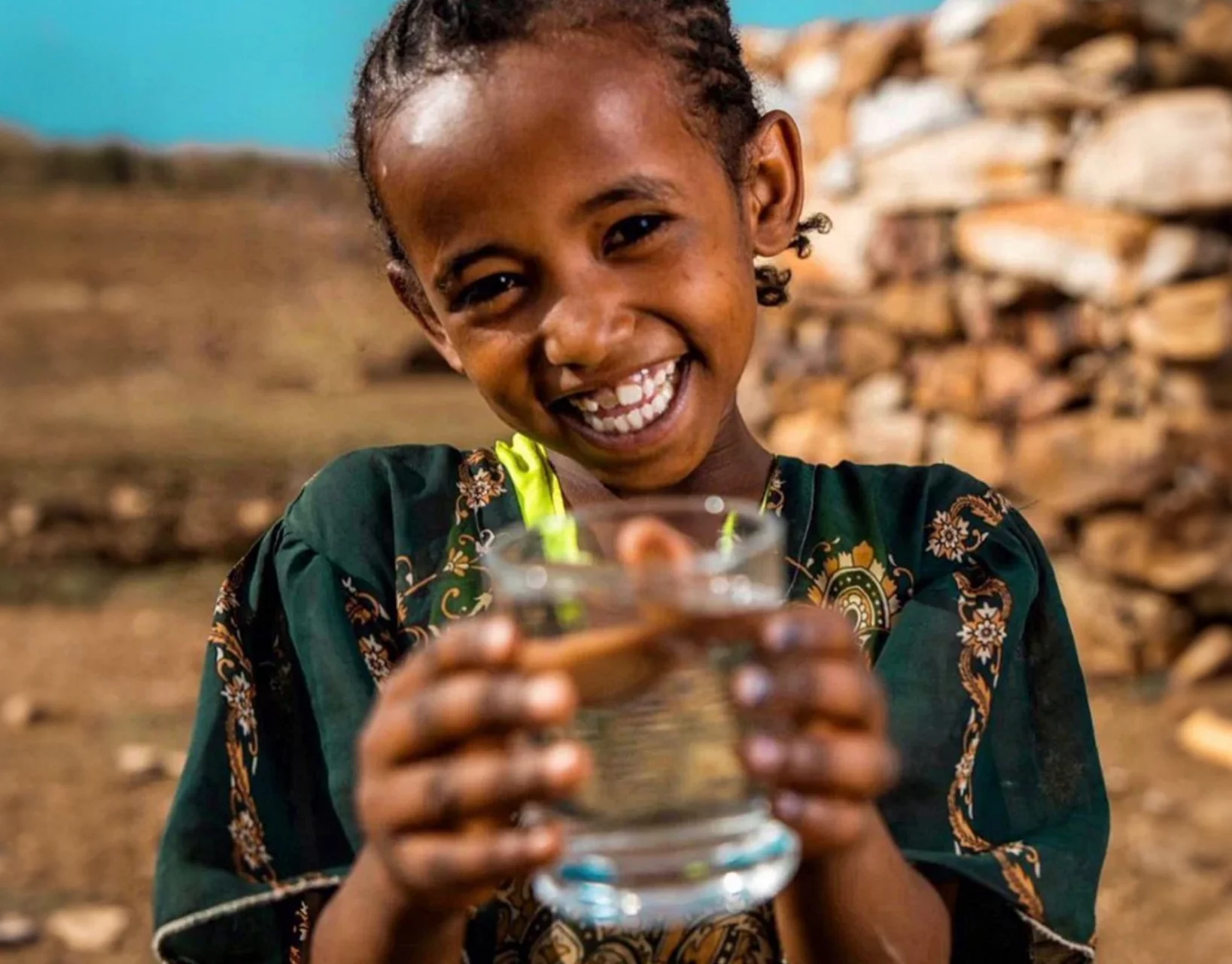 Young girl holding a glass of clean drinking water in Ethiopia