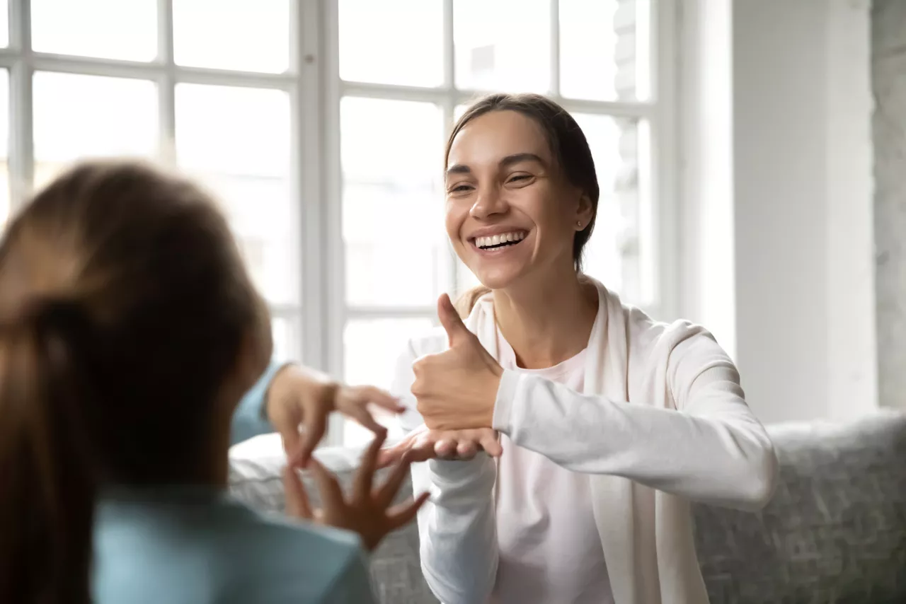 Smiling Caucasian woman learn sign language with little kid