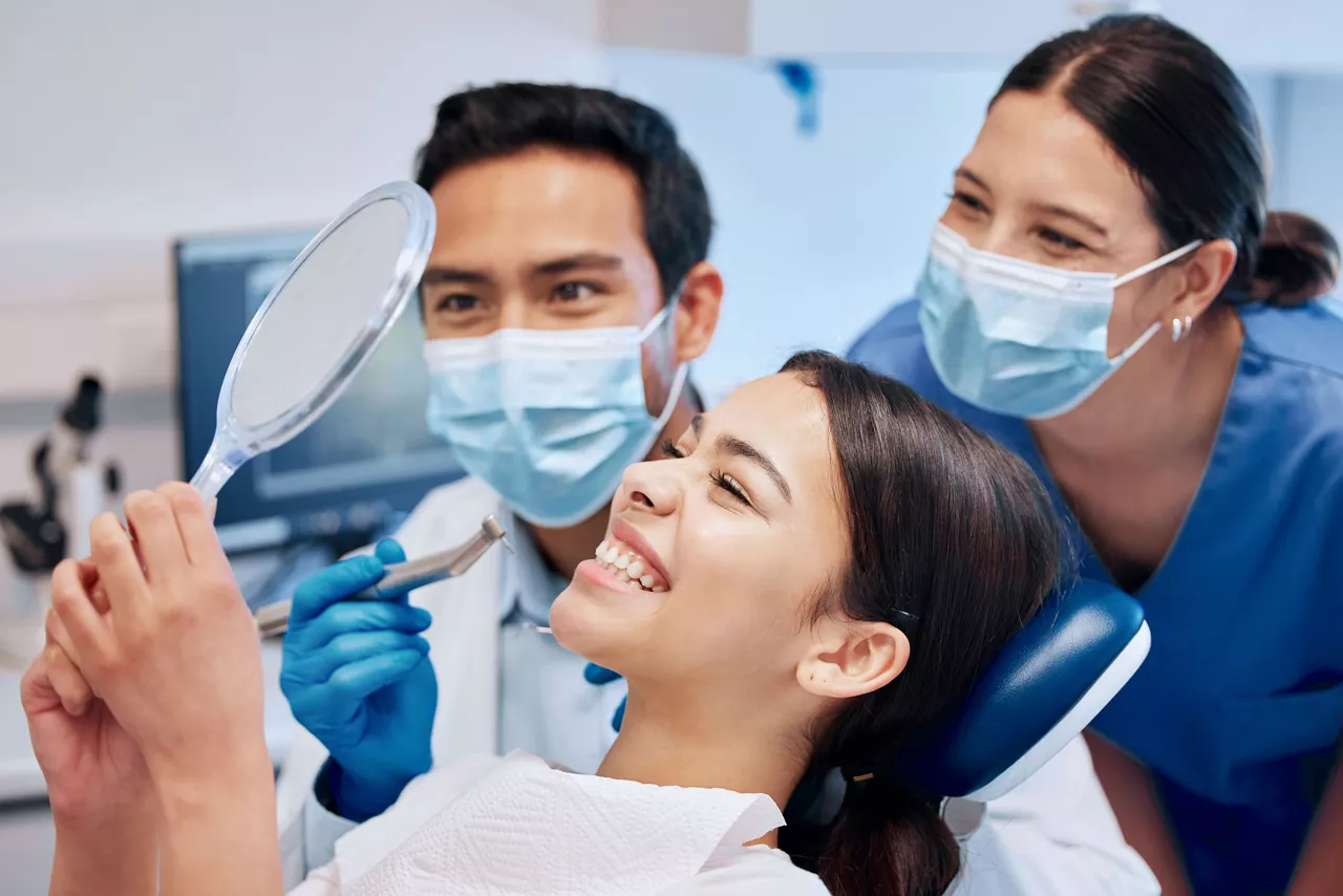 Dentist, mirror and woman with smile in consultation for teeth whitening, service and dental care. Healthcare, dentistry and female patient with orthodontist for oral hygiene, wellness and cleaning.