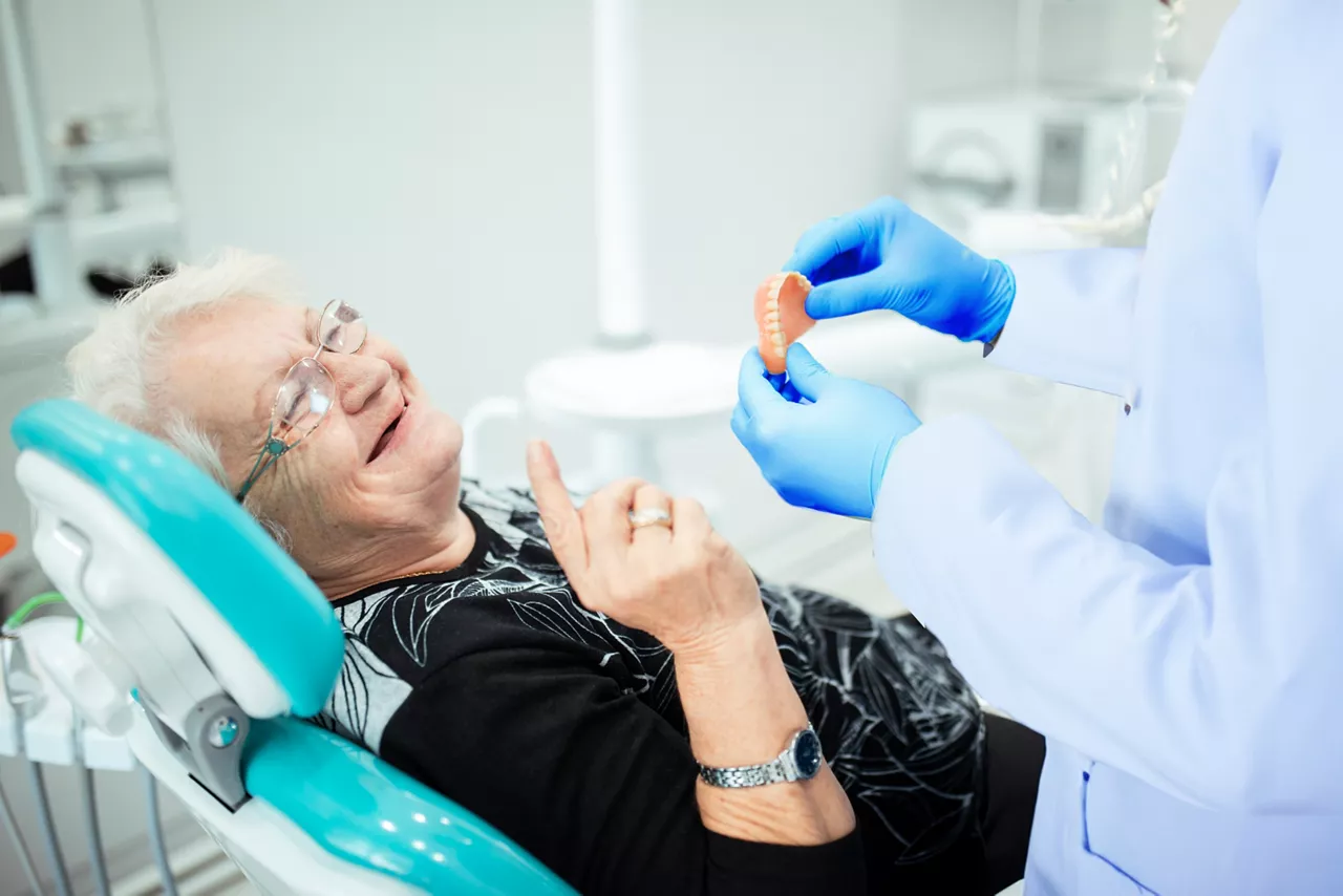 woman receiving dentures from dentist