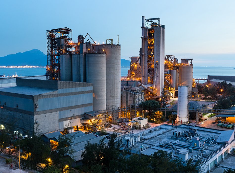 Night view of power generation plants illuminated, featuring electricity towers against a dark sky.
