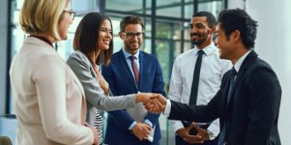 Group of men and women smiling and shaking hands