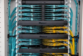 Rows of clean fiber cabling in turquoise and yellow within a data center cabinet