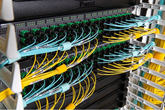 A side view close-up of blue and yellow fiber optic cable in server room