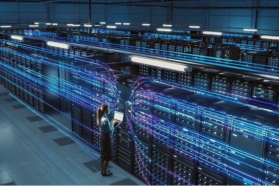 Data center racks and woman with laptop in her hand standing and looking at laptop