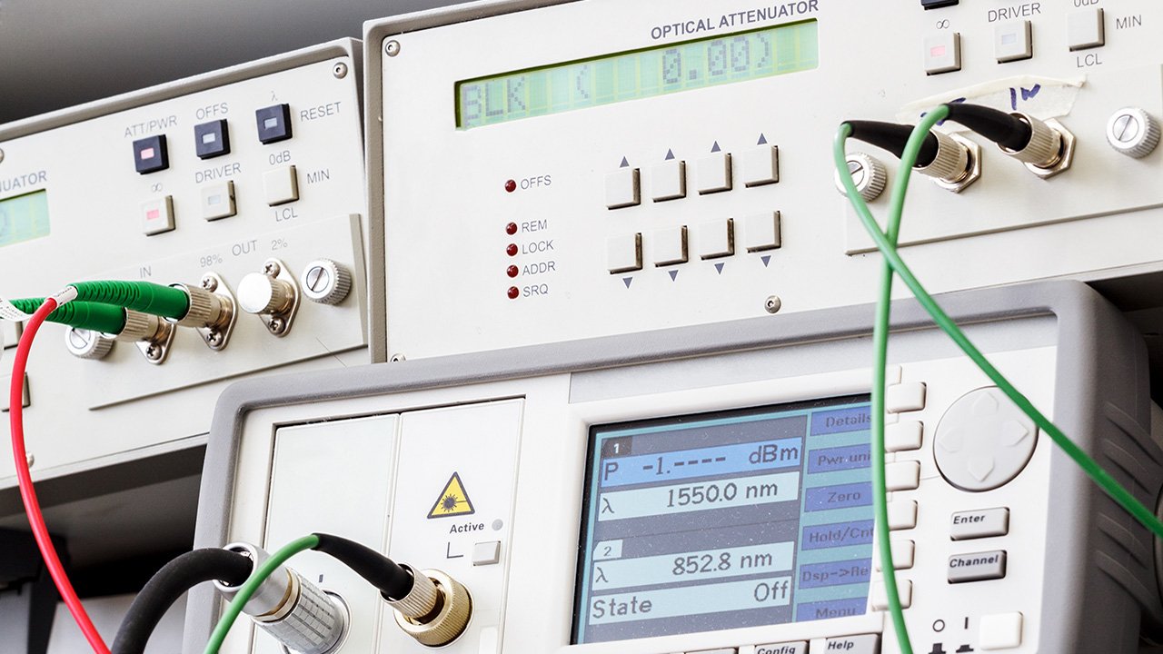 Lab equipment with buttons, dials and readouts, with red, green, and black cables connected for testing