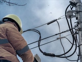 Utility employee in hard hat on electricity pole outdoor