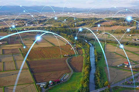 A rural landscape with farmland, farms, and a small city in the background, with bouncing points of light that represent data transfer