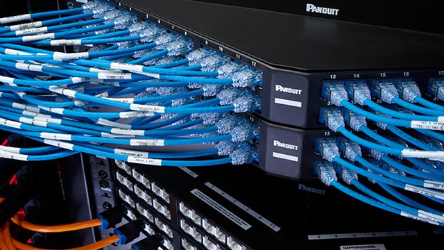 Angled panel installed in a rack, with jacks and patch cords connected. 