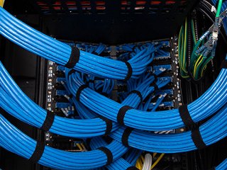 bundles of blue category 6A cable on the back side of a telecommunications rack.