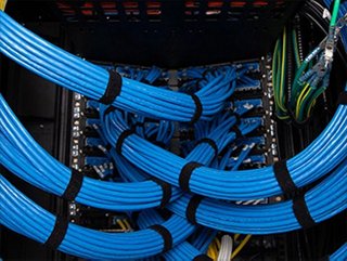 large bundles of blue copper cable on the back side of a telecommunications rack