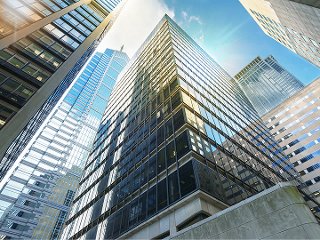 Skyscraper office buildings in city during the day looking up from ground level.