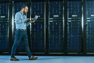 Engineer walking along server racks in a colocation data center