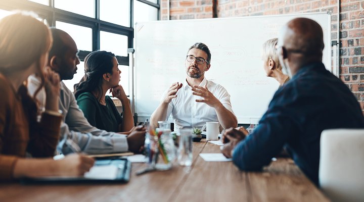 A man leading a meeting in boardroom with coworkers