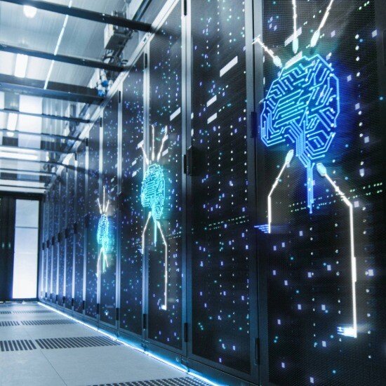 Data Center manager working on a laptop while standing in front of illuminated server racks inside an Edge data center environment