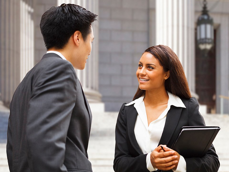 Businesswoman standing outside of a building looking at a colleague
