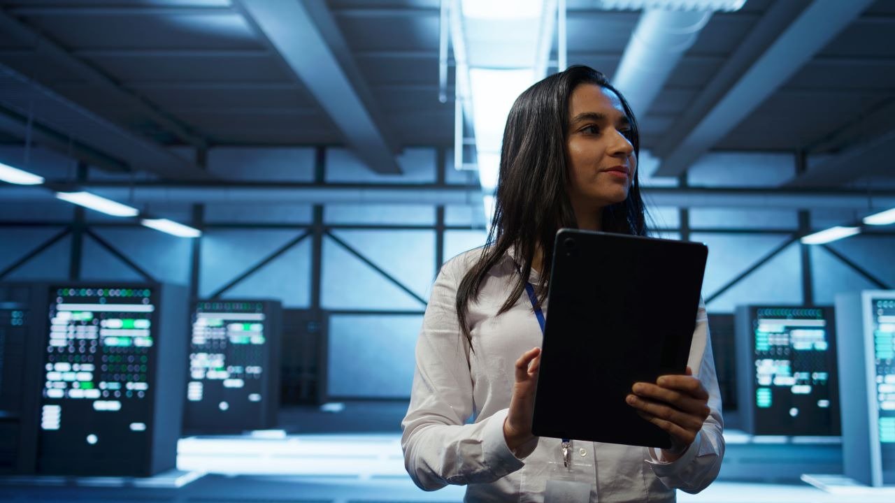 A woman holding a tablet computer is focused on the contents of the screen.