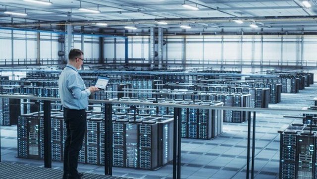 An engineer looking over rows of data center cabinets