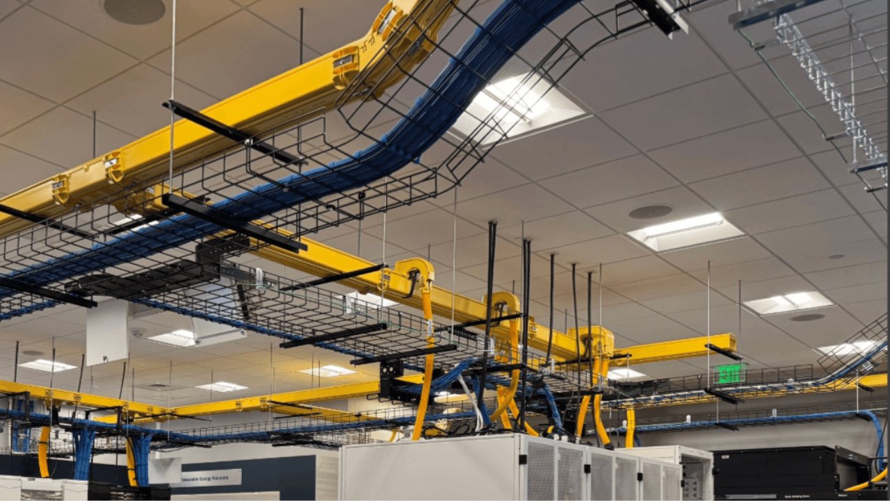 Data Center Manager walking through data center aisle with cable routing system above.