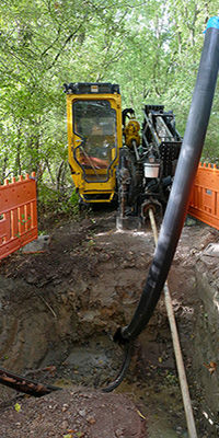 a drilling machine for laying fiber optic cable, drilling horizontally through the ground, with orange safety barricades