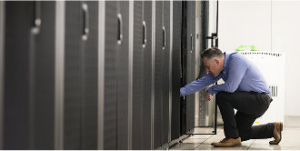 A data center manager examines the inside of an on-premises cabinet
