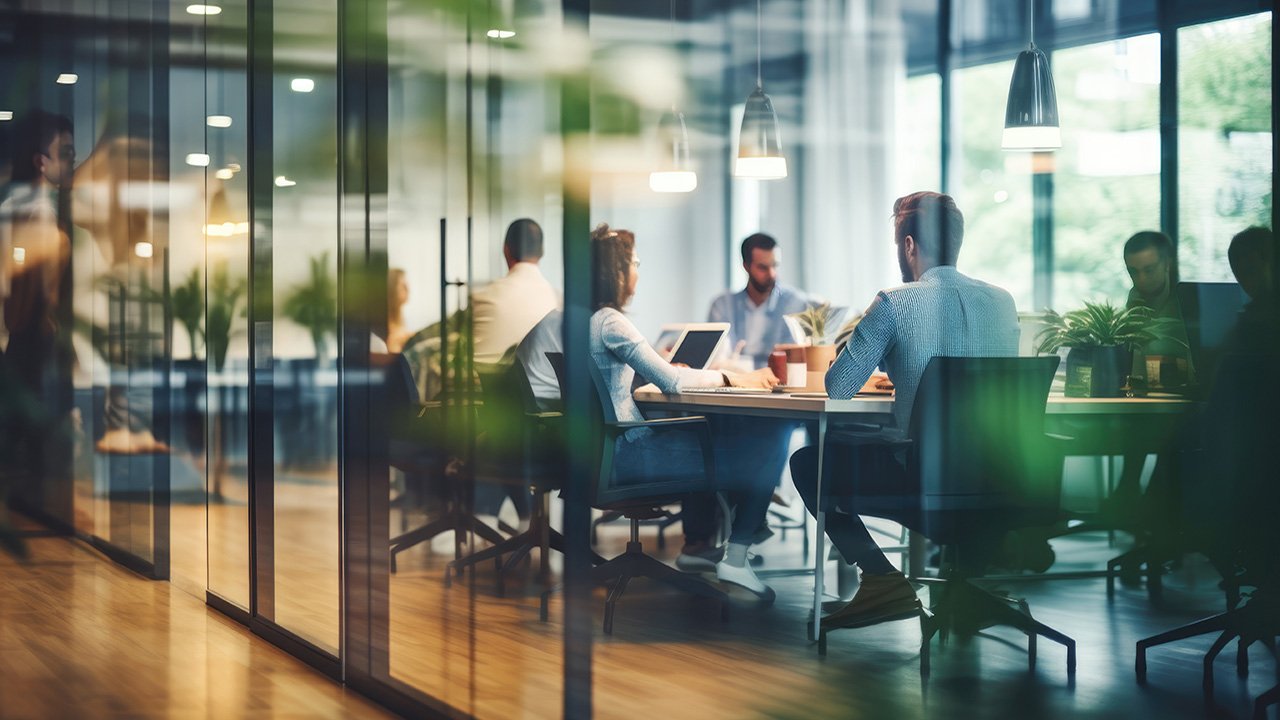 A blurred vision of a busy office building with people meeting around a conference room table