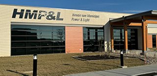 Exterior view of a brick and stone building with a sign for Henderson Municipal Power & Light on the front