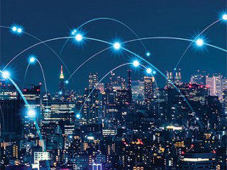 Brightly lit cityscape against a dark sky, with points of light arcing through the sky