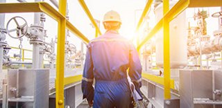 Industrial worker in hard hat walking through chemical processing facility