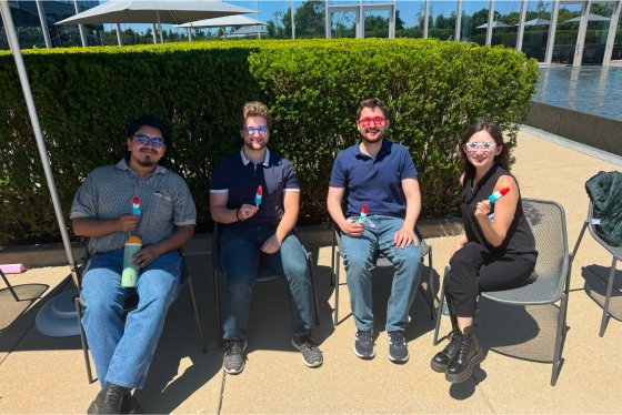 Four people sitting in chairs with fun sunglasses and ice cream