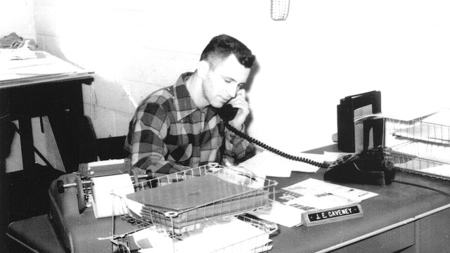 Founder Jack E. Caveny sitting at desk on phone