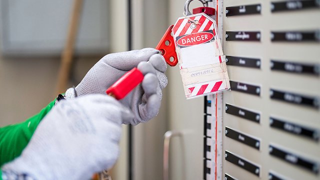 Worker unlocking lockout/tagout equipment to access a panel