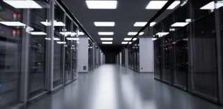 A hallway of a data center, with light panels on the ceiling and the data servers on both sides. 