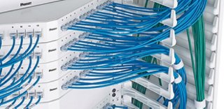 A view of wire routing with bunches of blue wires connecting to a white enclosure.