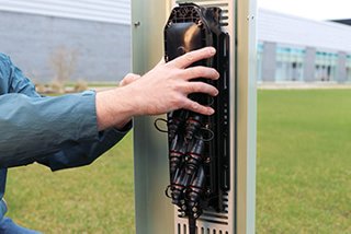An open broadband pedestal with a person’s hand installing a multiport service terminal