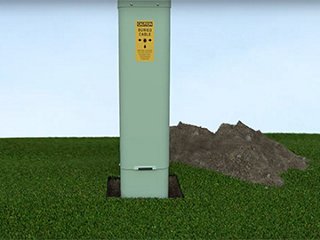 a green fiber optic pedestal with a mound of dirt beside it