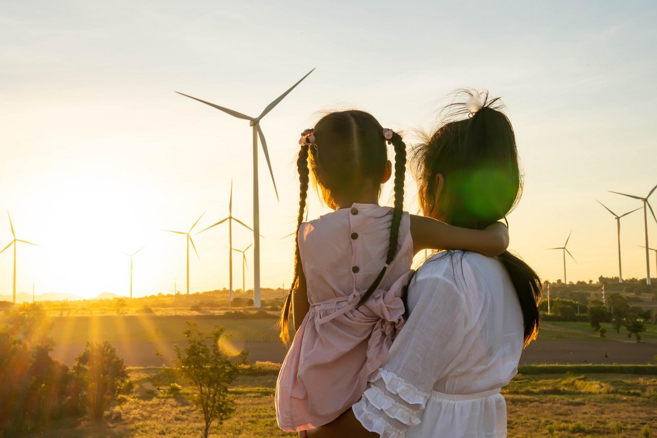 Mother and Daughter Watching Wind Turbines at Sunset