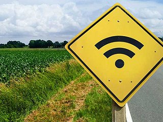 Yellow sign with WiFi symbol on rural road.