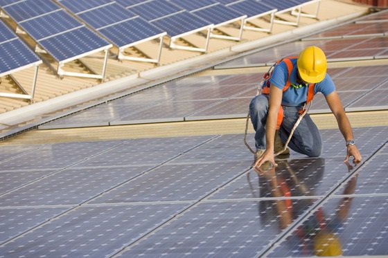 A worker in a hard hat and safety vest is engaged in solar panel installation, representing Panduit's focus on sustainable energy.