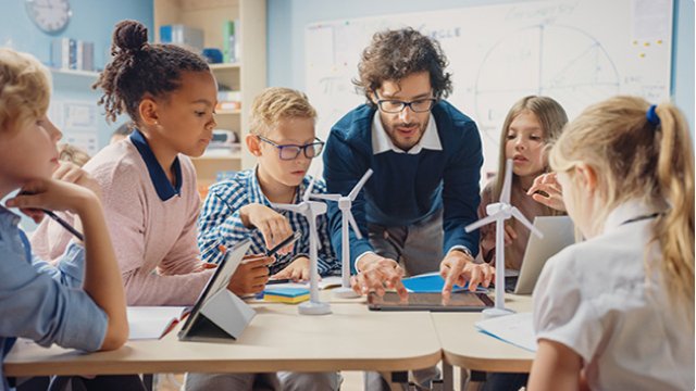 A teacher and students work with wind turbine models in a classroom