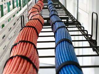 2 bundles of copper cables, one red and one blue, side by side in a cable tray